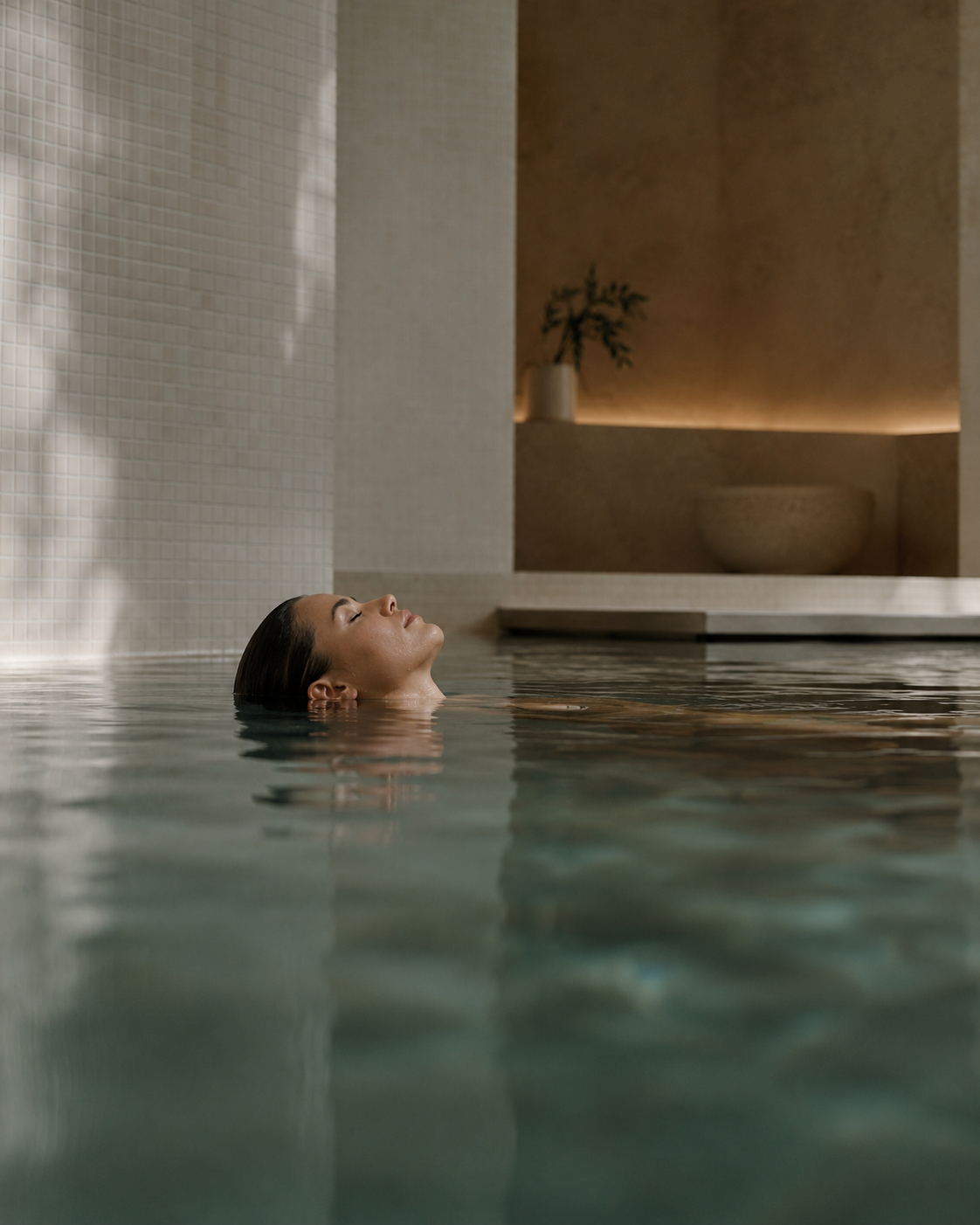 Woman relaxing in a tranquil indoor spa pool, reflecting SLOAID's slow skincare philosophy, wellness, skin recovery, and mindful self-care